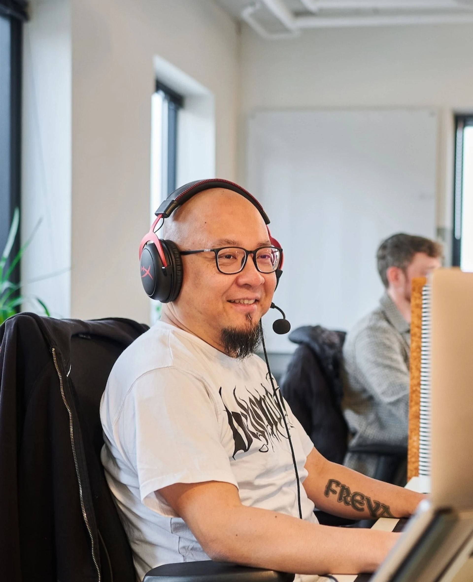 Man met headset werkt aan computer in een kantooromgeving.