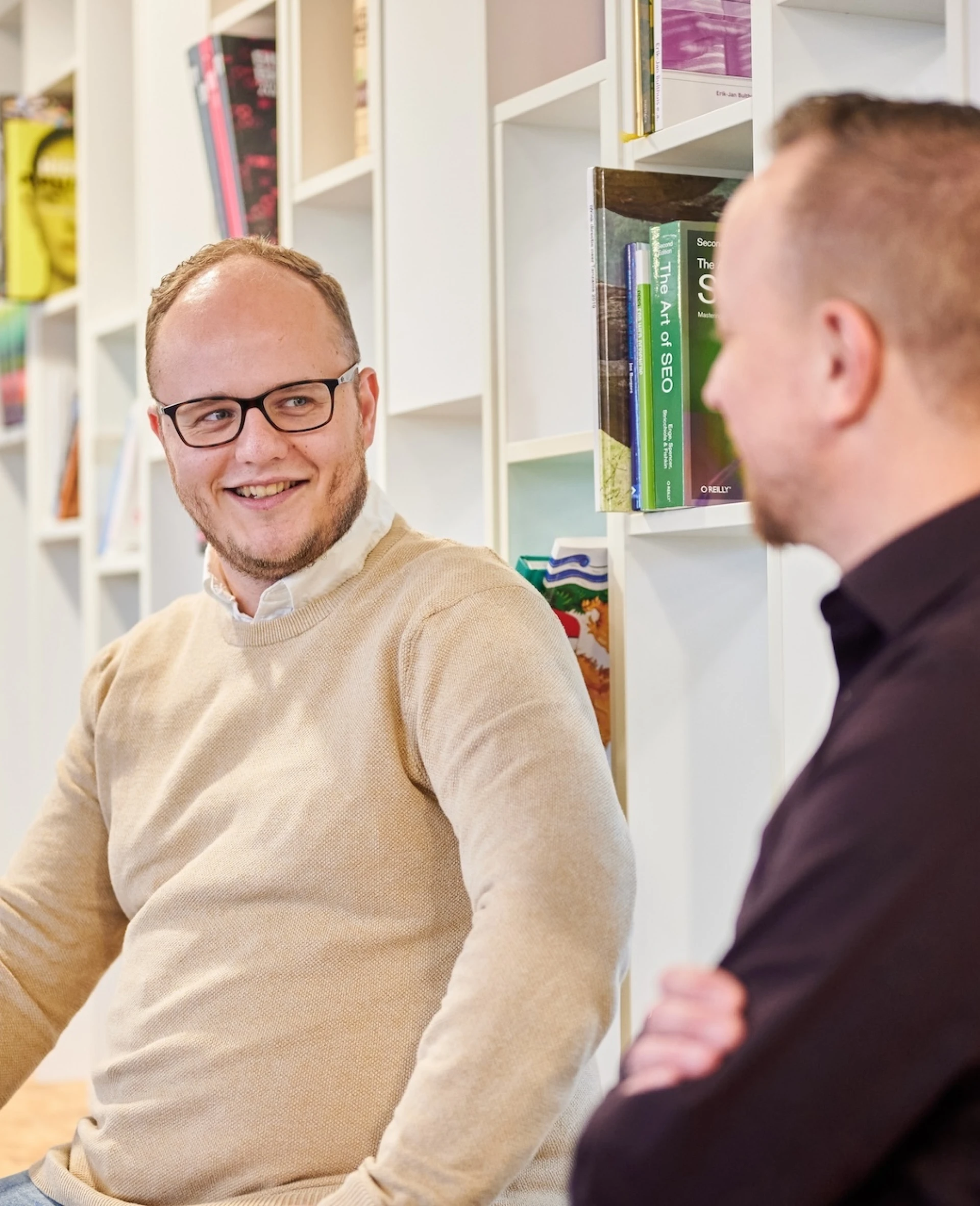 Twee mannen in gesprek in een moderne kantooromgeving.
