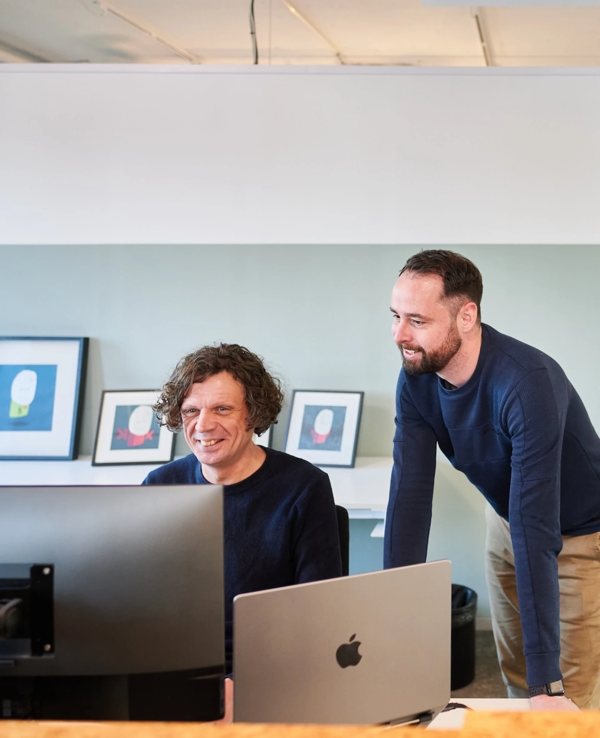 Twee collega's werken samen aan een computer in een kantoorruimte.