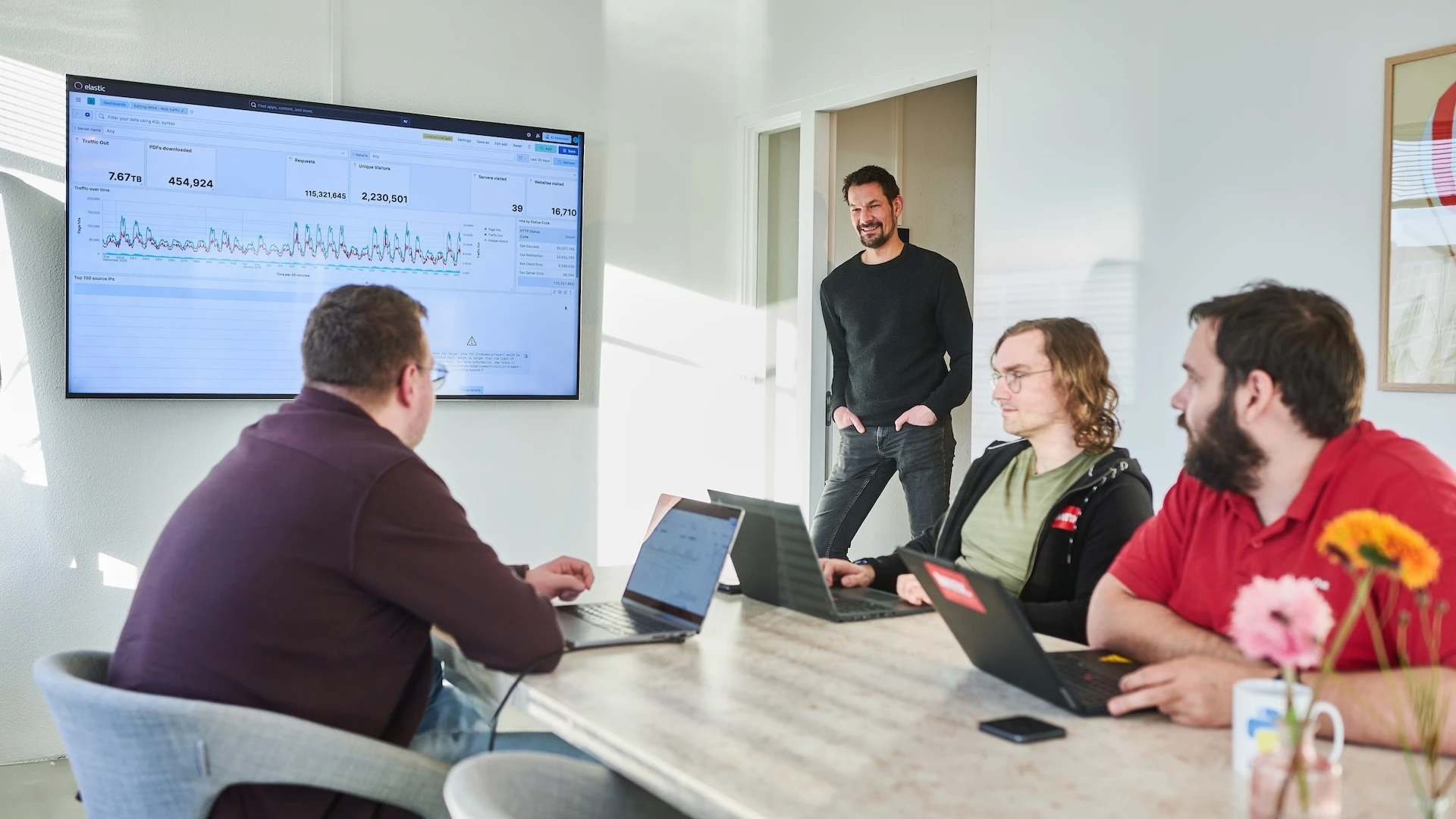 Een teamvergadering met laptops en een presentatiescherm.