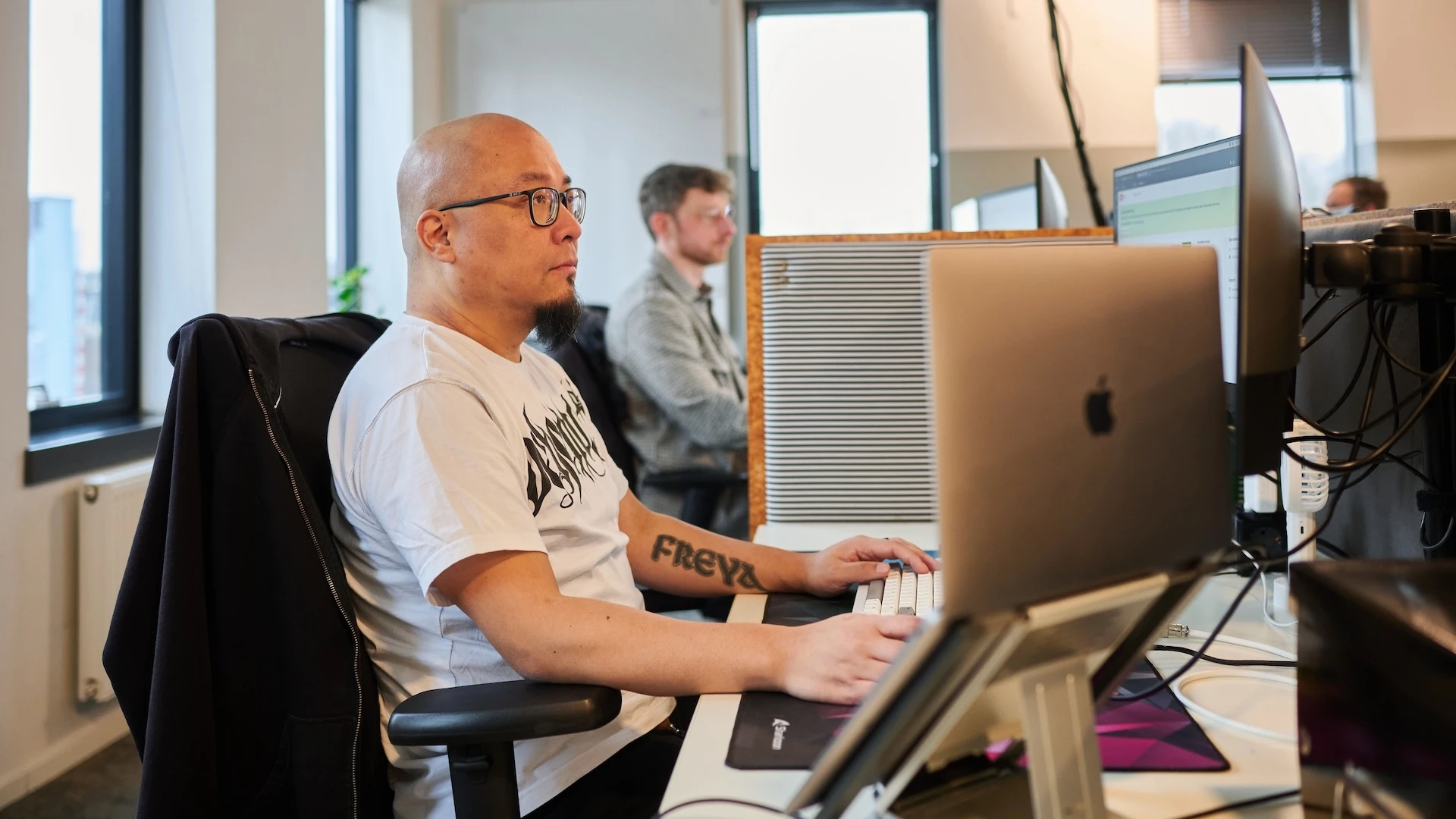 Een man werkt aan een bureau met een computer in een kantooromgeving.