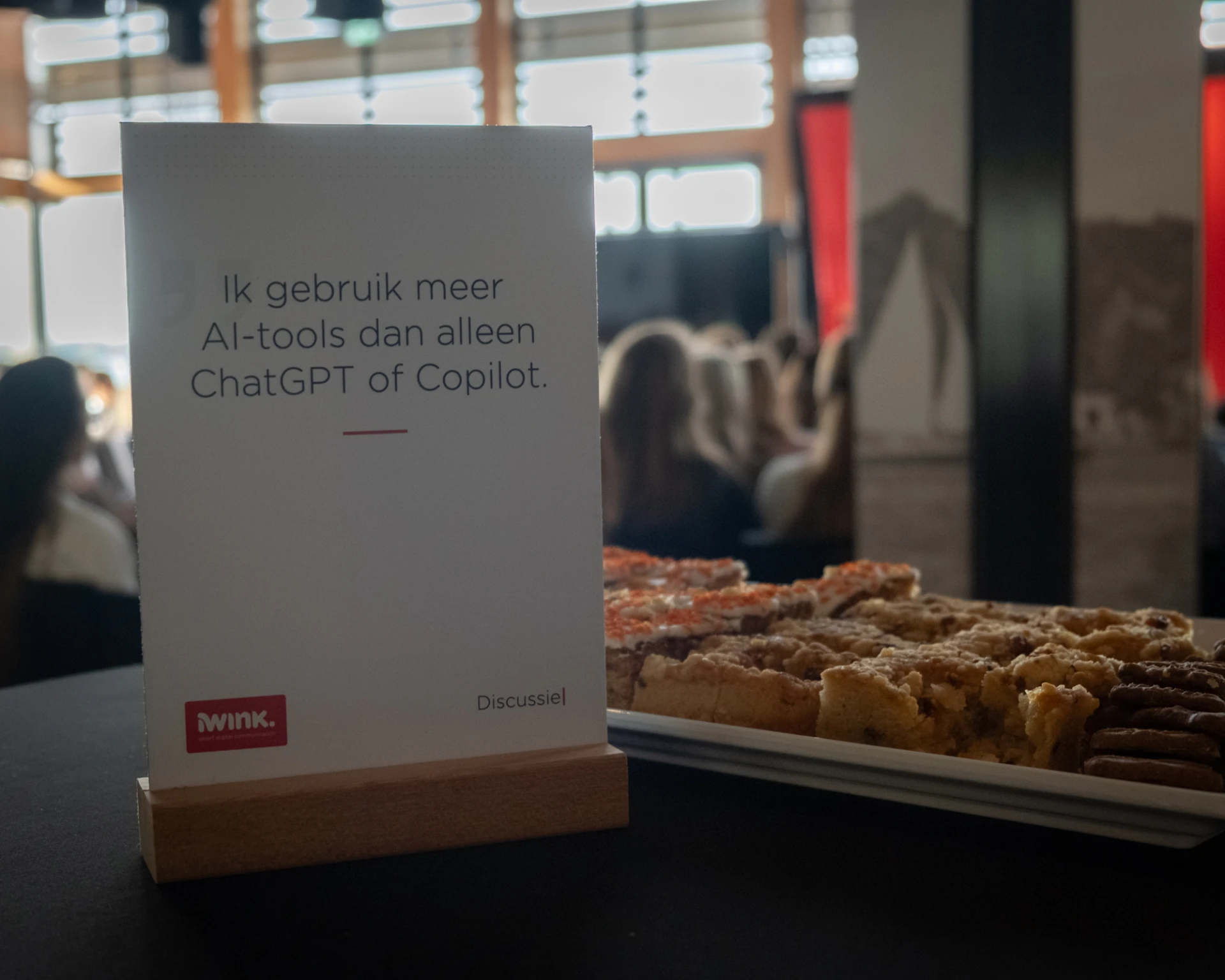 Een bord met tekst naast een schaal met gebakjes van iWInk