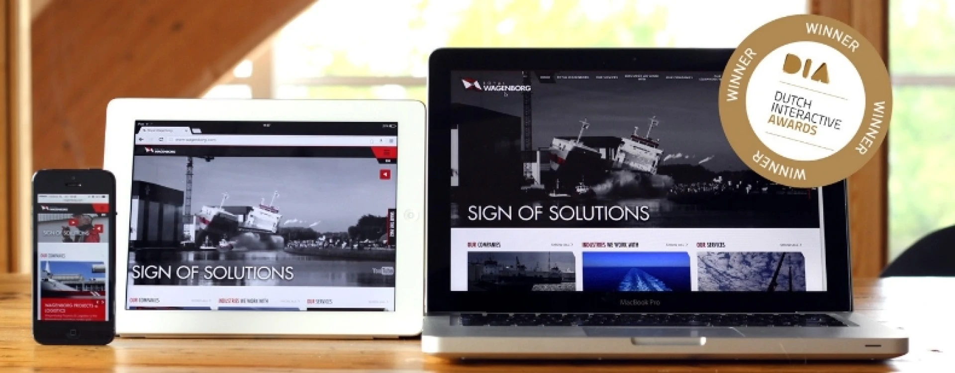 Een smartphone, tablet en laptop tonen dezelfde website met een "DIA" award embleem.