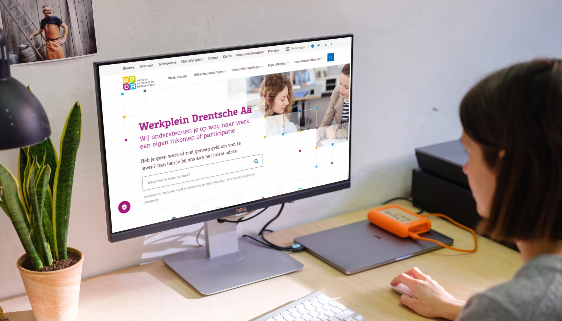 Persoon werkt op een computerbureau met een ingeschakeld beeldscherm.