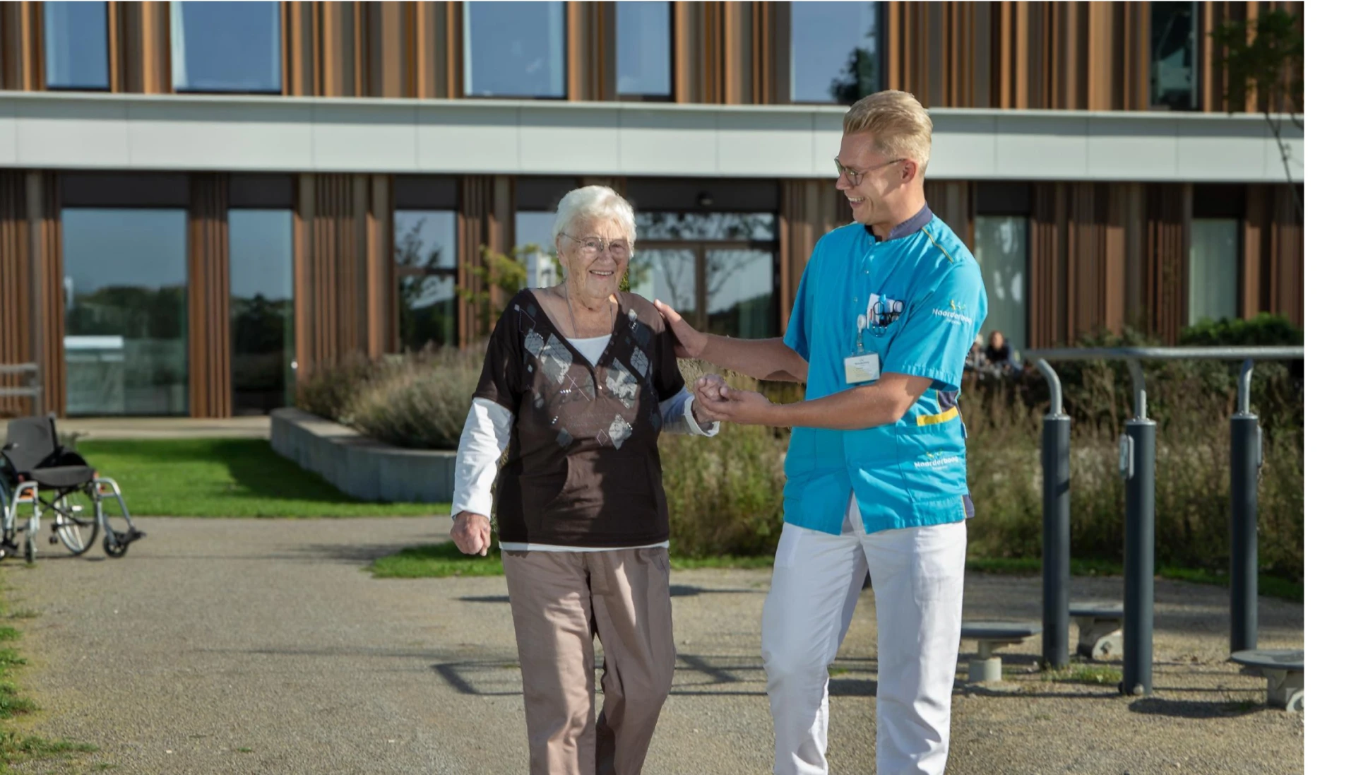 Een zorgverlener helpt een oudere vrouw buiten te wandelen.