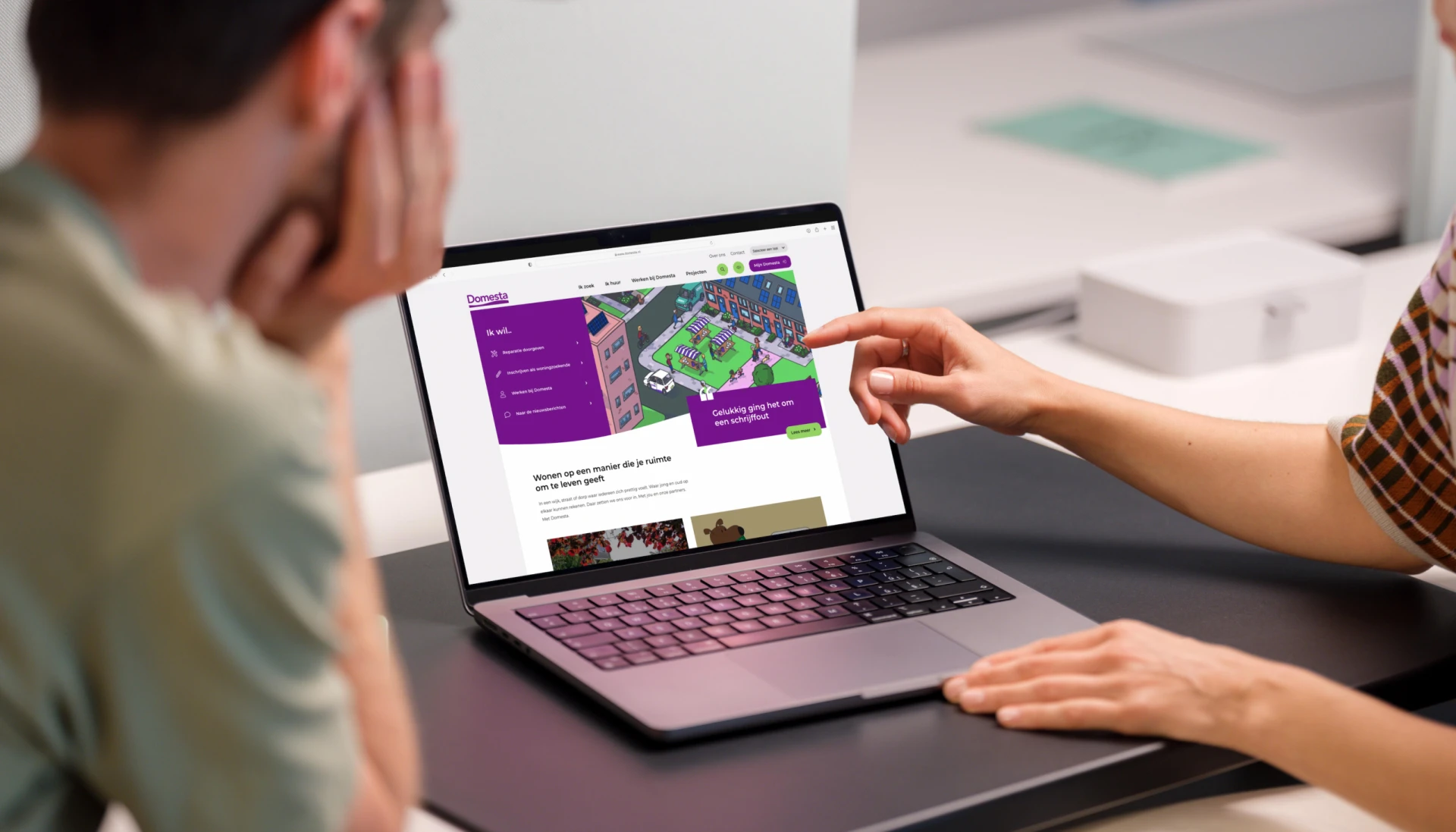 Twee personen bekijken samen een website op een laptop.