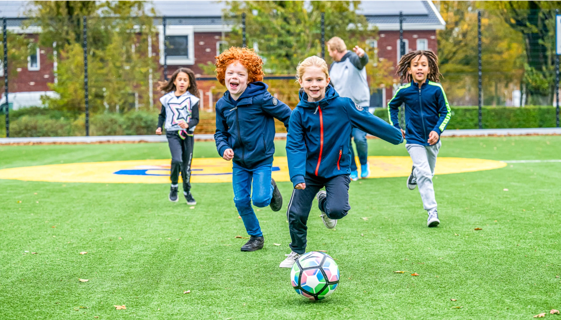 Kinderen spelen voetbal op een grasveld.