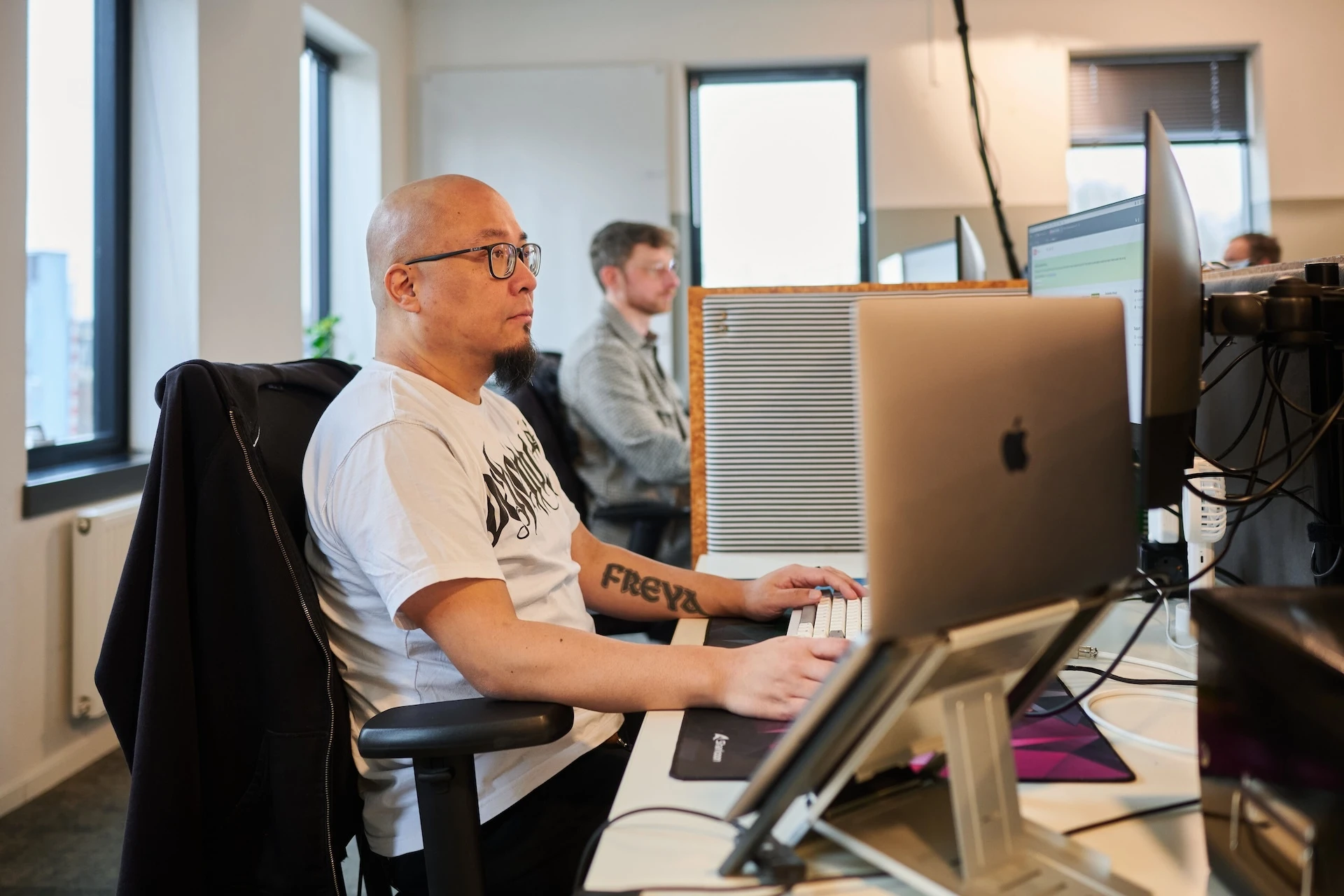 Een man werkt aan een bureau met een computer in een kantooromgeving.
