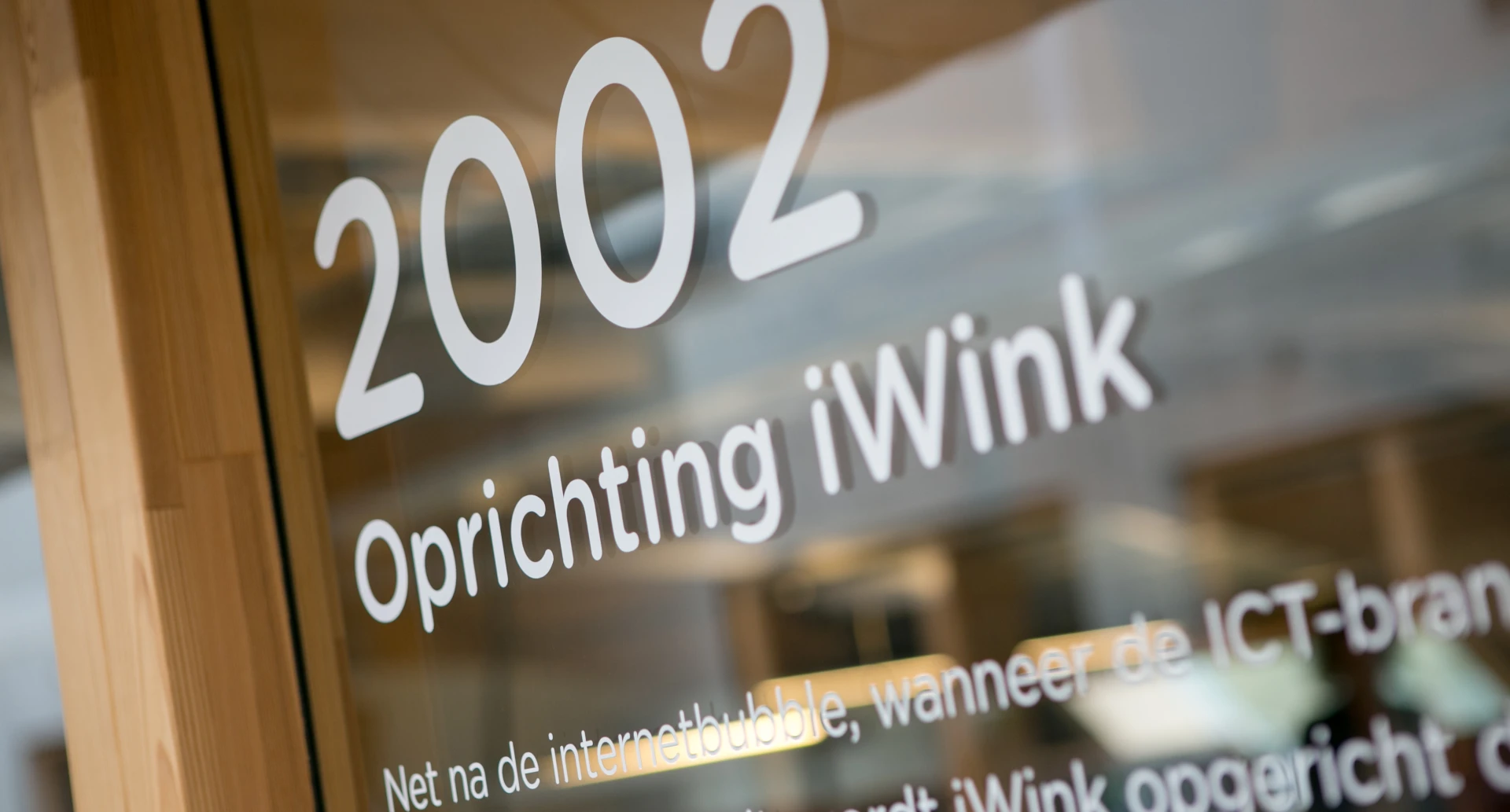 Tekst op glas met "2002 Oprichtingsjaar iWink".