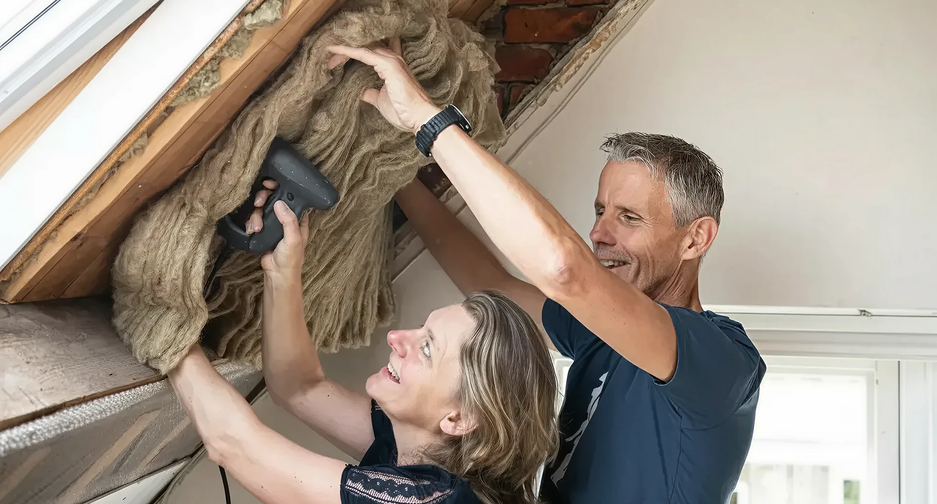 Man en vrouw isoleren samen een dak met isolatiemateriaal.
