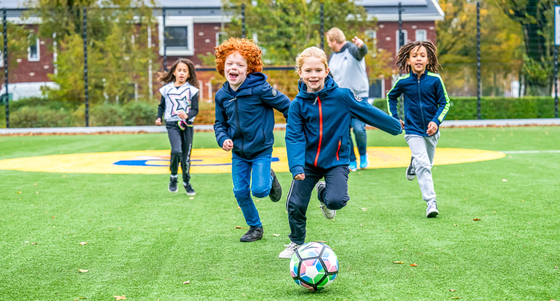 Kinderen spelen voetbal op een grasveld.