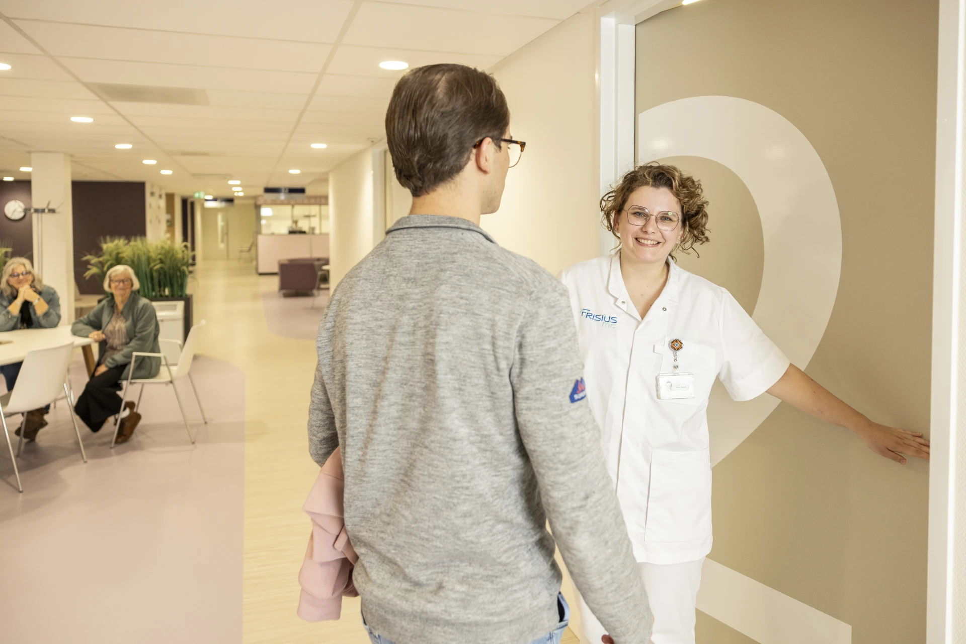 Een patiënt wordt verwelkomd door een medisch personeelslid in een kliniek.
