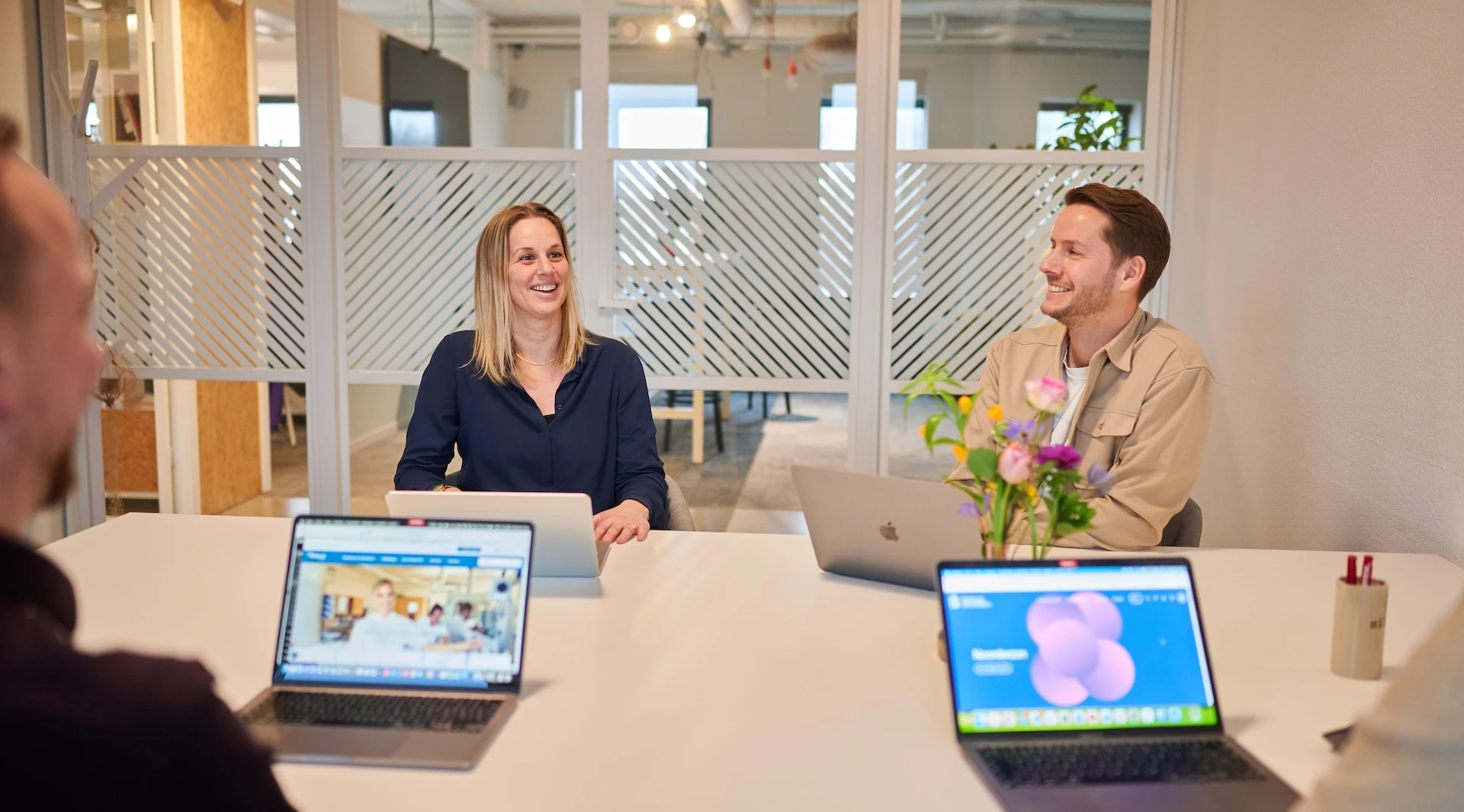 Mensen in een vergaderruimte met laptops.