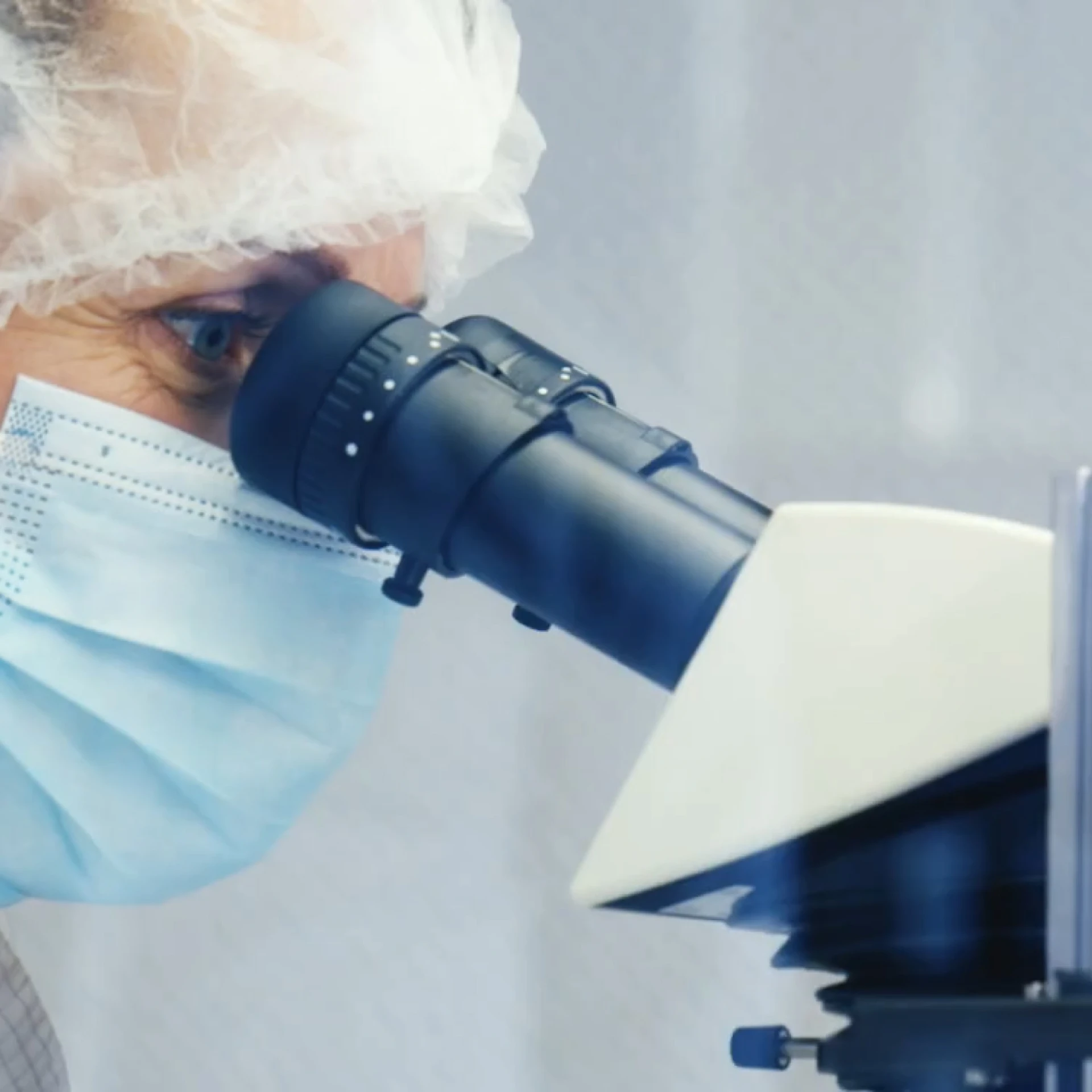 Een wetenschapper kijkt door een microscoop.