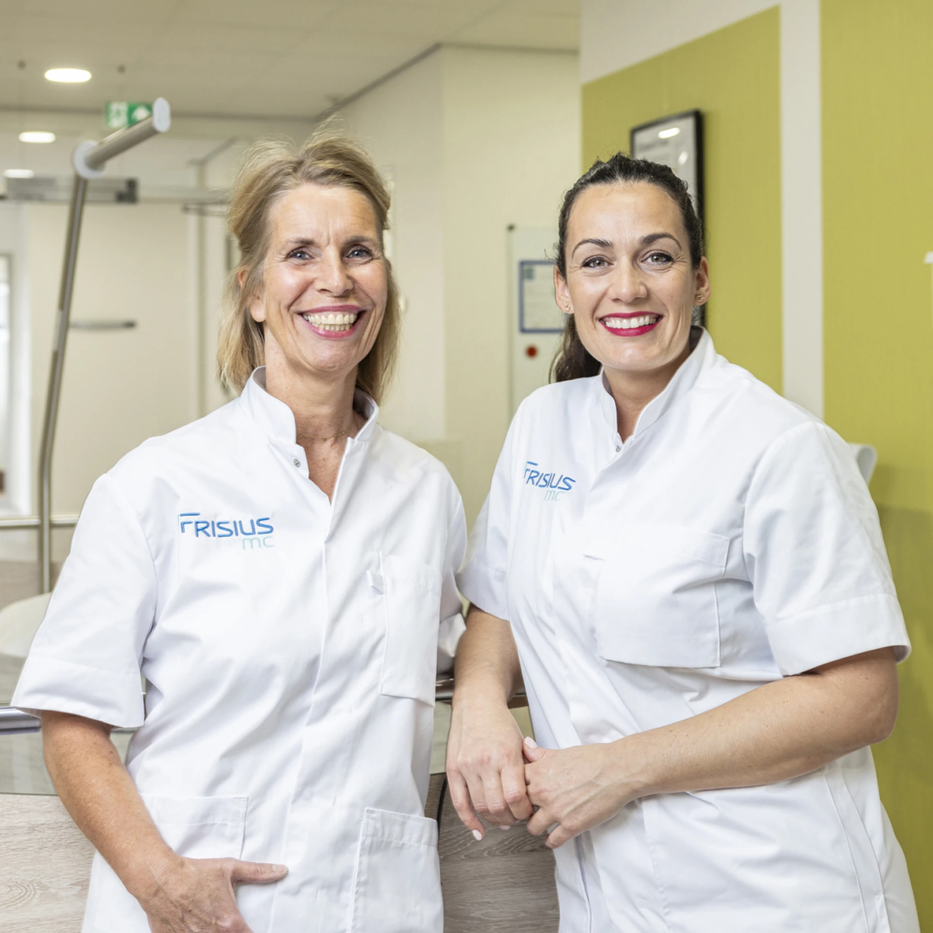 Twee lachende tandheelkundige professionals in een kliniek.