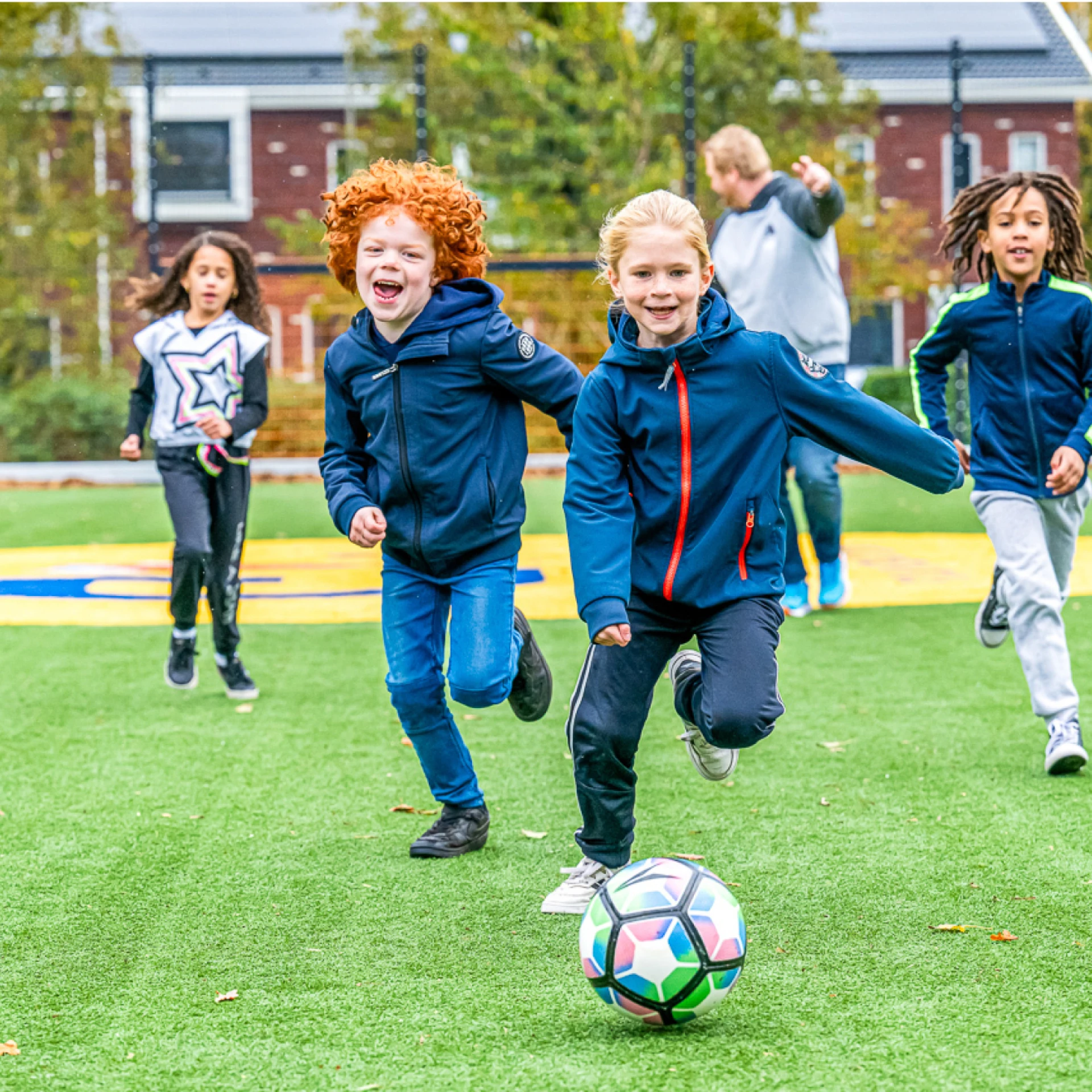 Kinderen spelen voetbal op een grasveld.
